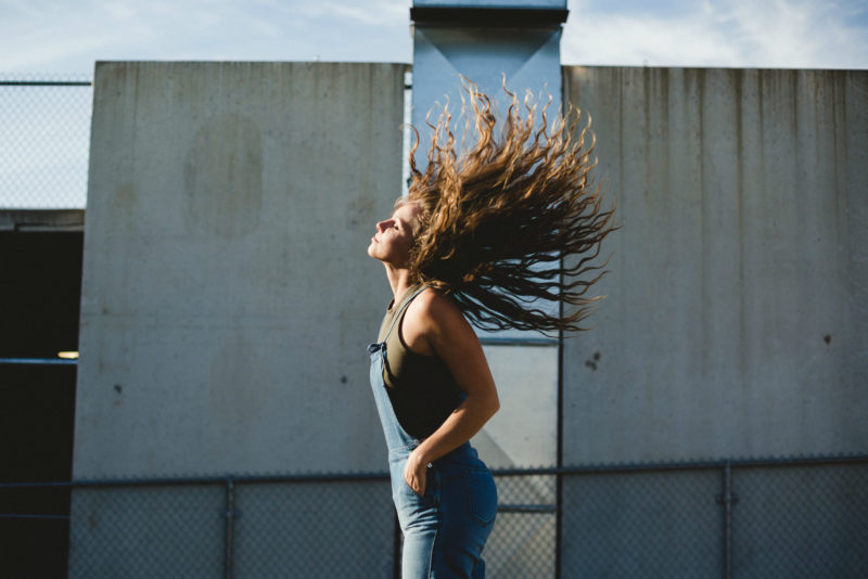 KaS stands facing the sun, curly hair flipped straight back with a look of contentment.