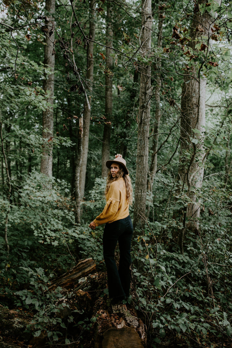 Woman looks over shoulder at camera as she walks on a log.